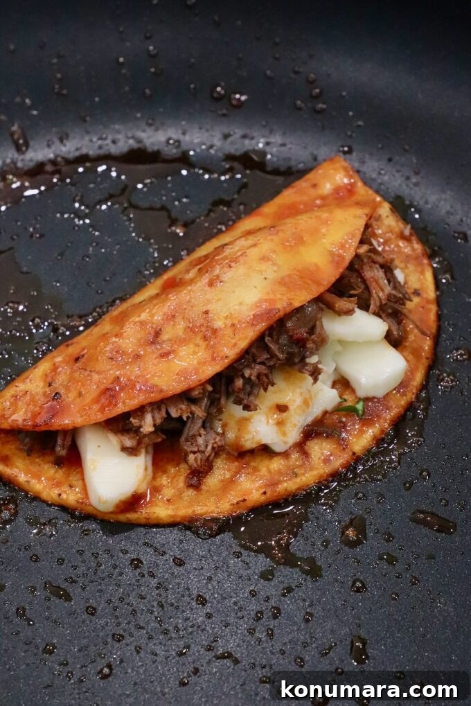 Quesabirria Recipe: Crispy Cheesy Birria Tacos 5 quesabirria taco in skillet