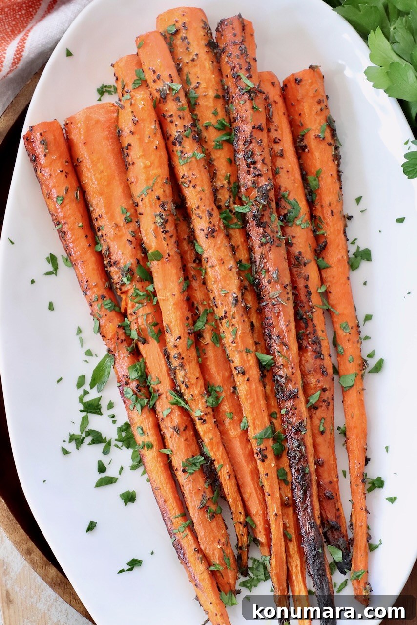 Oven-Roasted Carrots with Honey and Garlic 2 roasted carrots topped with fresh chopped parsley on white plate