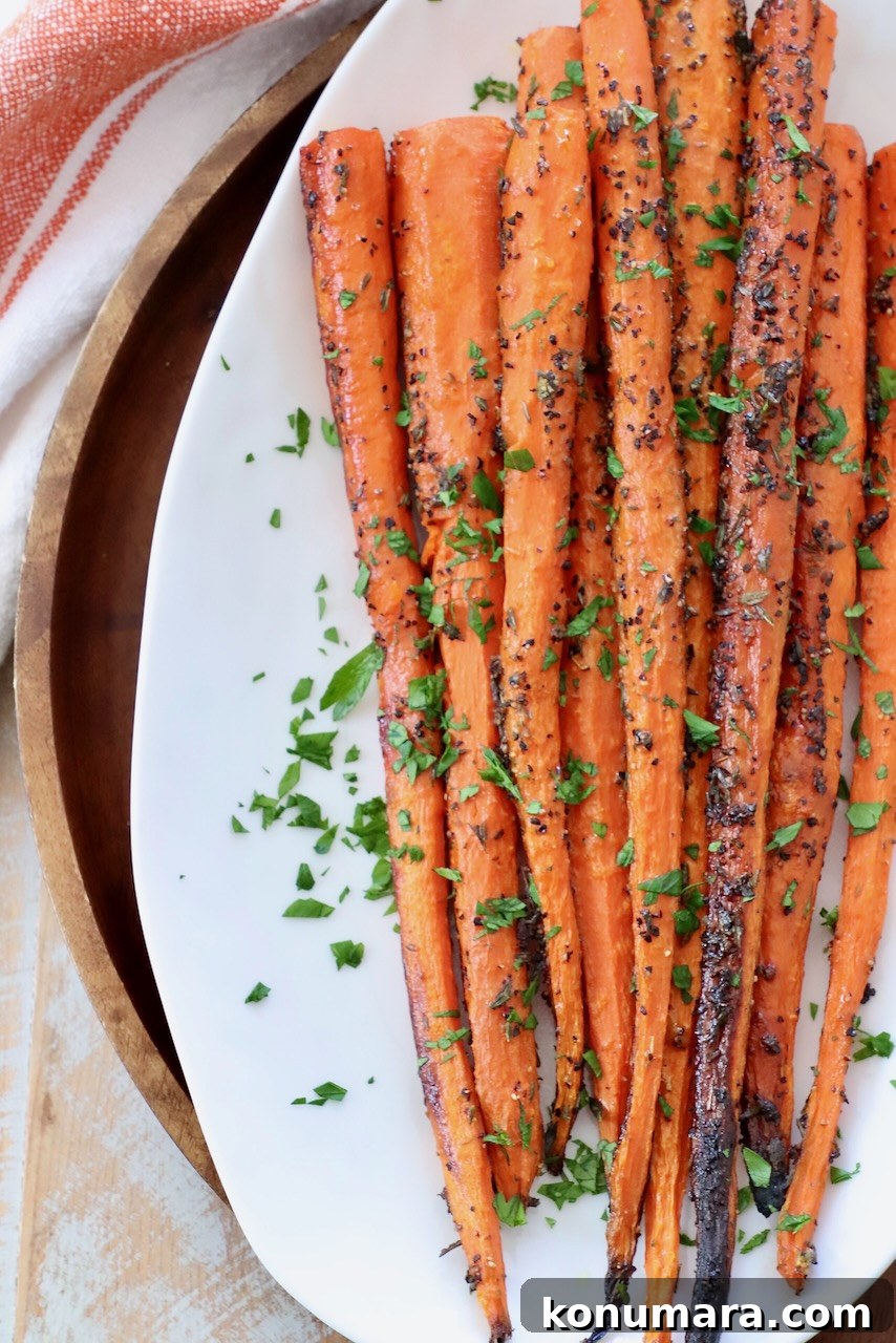Oven-Roasted Carrots with Honey and Garlic 6 whole roasted carrots on white plate with fresh herbs