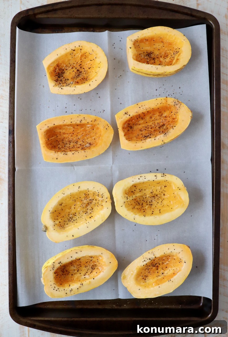Delicata squash sliced in half and seasoned on a baking sheet