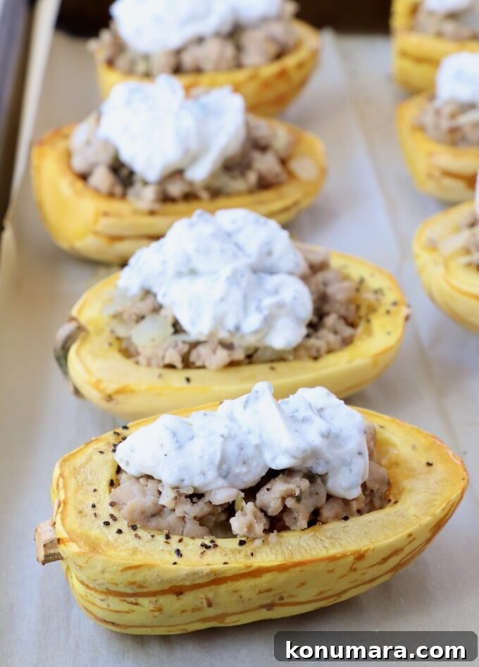 Roasted delicata squash halves filled with cooked sausage and ricotta cheese