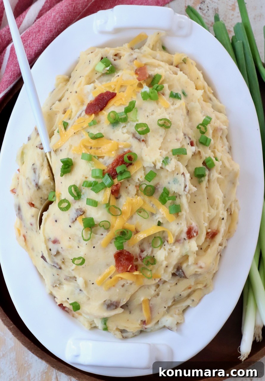 Loaded Mashed Potatoes Recipe with Bacon and Cheddar 2 mashed potatoes in serving dish topped with shredded cheddar and diced green onions