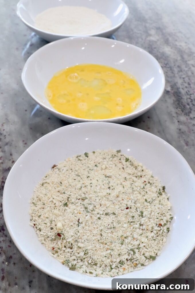 three bowls filled with breadcrumbs, whisked eggs and flour