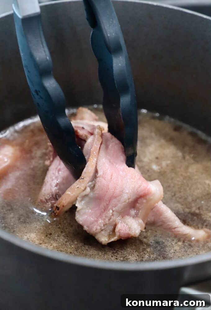 Classic Roast Beef Sandwich Recipe with Horseradish 6 tongs holding beef in pot of boiling beef broth