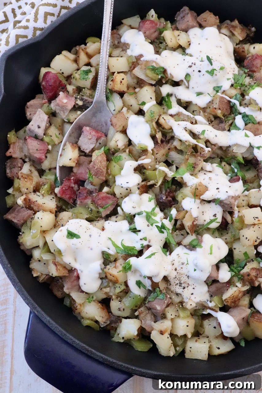 Skillet Philly Cheesesteak Hash with Peppers and Onions 2 diced steak and potato hash in skillet, topped with cheese sauce