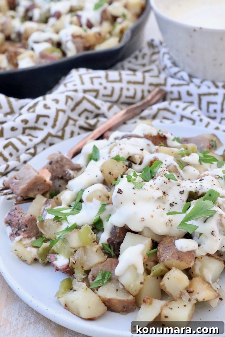Skillet Philly Cheesesteak Hash with Peppers and Onions 8 potato hash on plate covered with cheese sauce