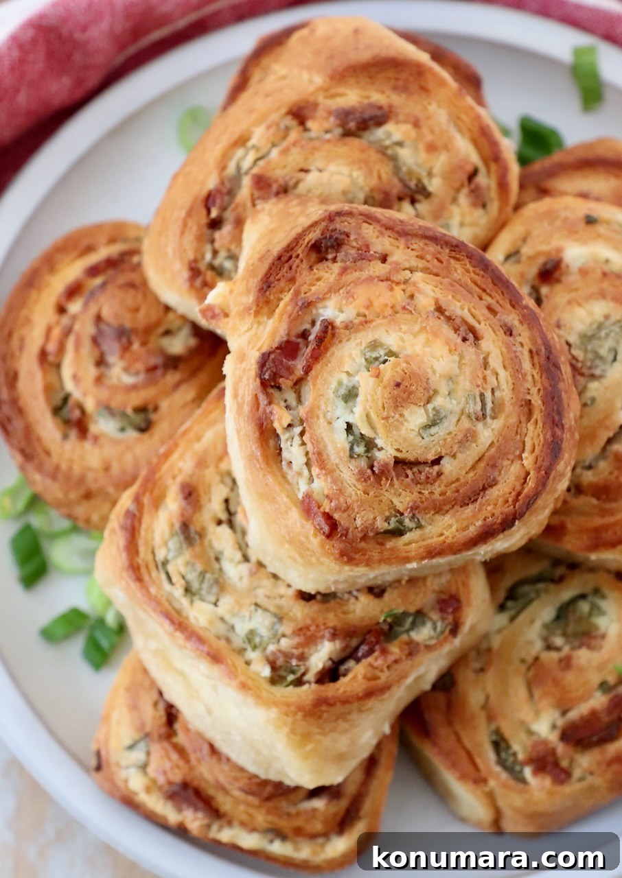 baked crescent rolls filled with bacon, cheese and green onions, stacked up on a plate