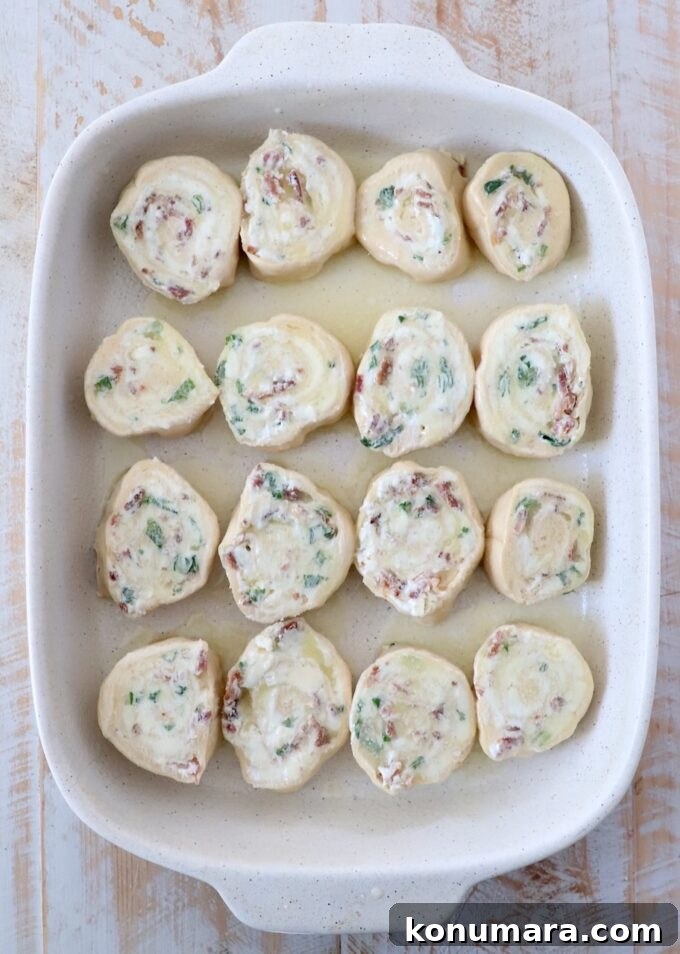 uncooked cheesy, bacon crescent rolls in a casserole dish, topped with melted butter