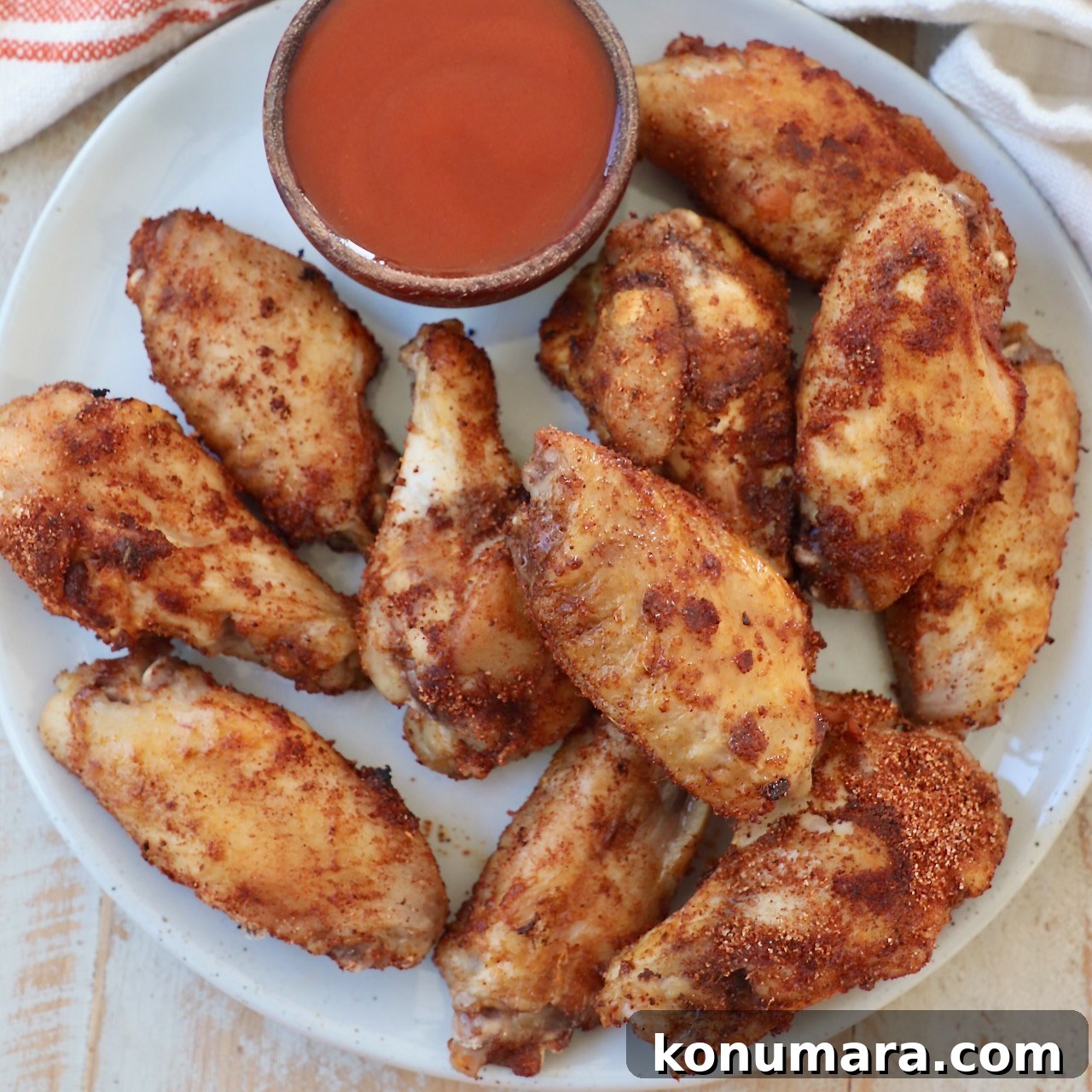 cooked chicken wings on plate with small bowl of buffalo sauce