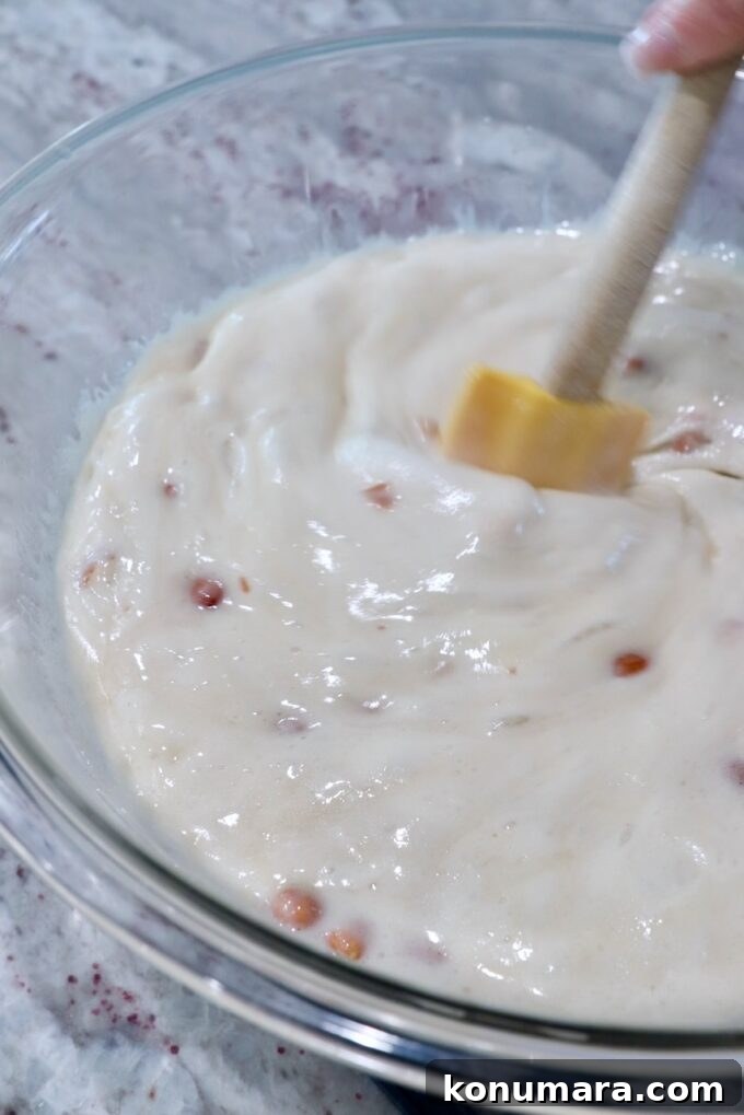 spatula stirring ingredients for peanut brittle together in a large glass bowl