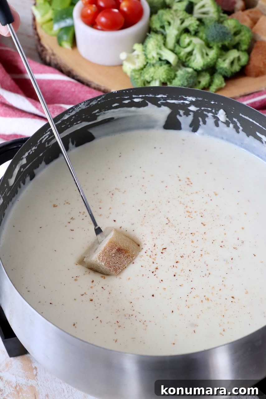 piece of bread dipped into cheese fondue in fondue pot