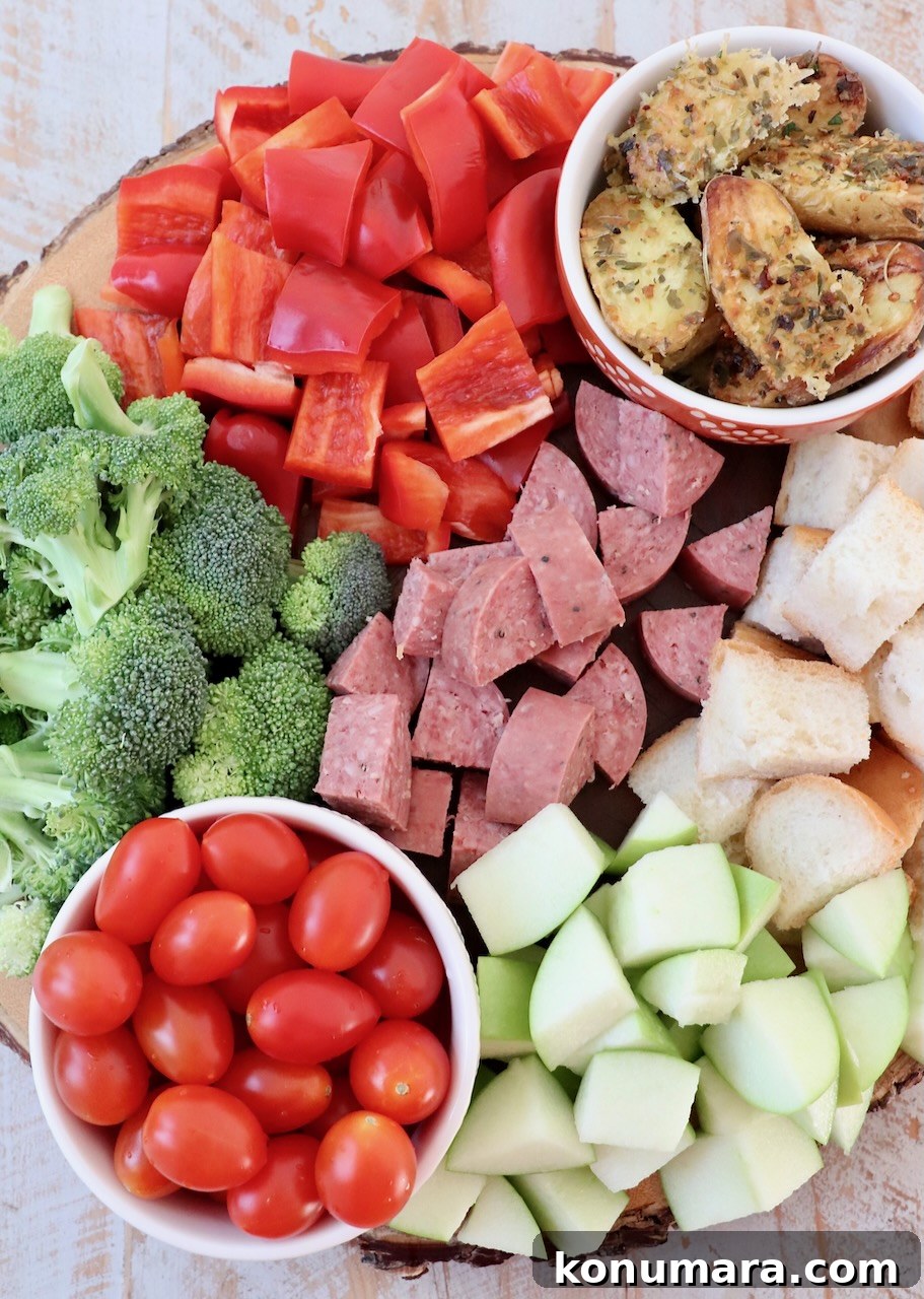 diced vegetables, apples, beef stick and cubes of bread on a wood tray