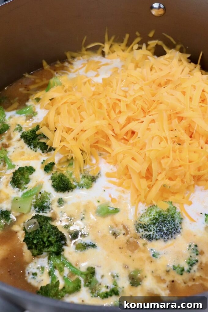 shredded cheese and half and half in pot with broccoli and seasoned chicken broth