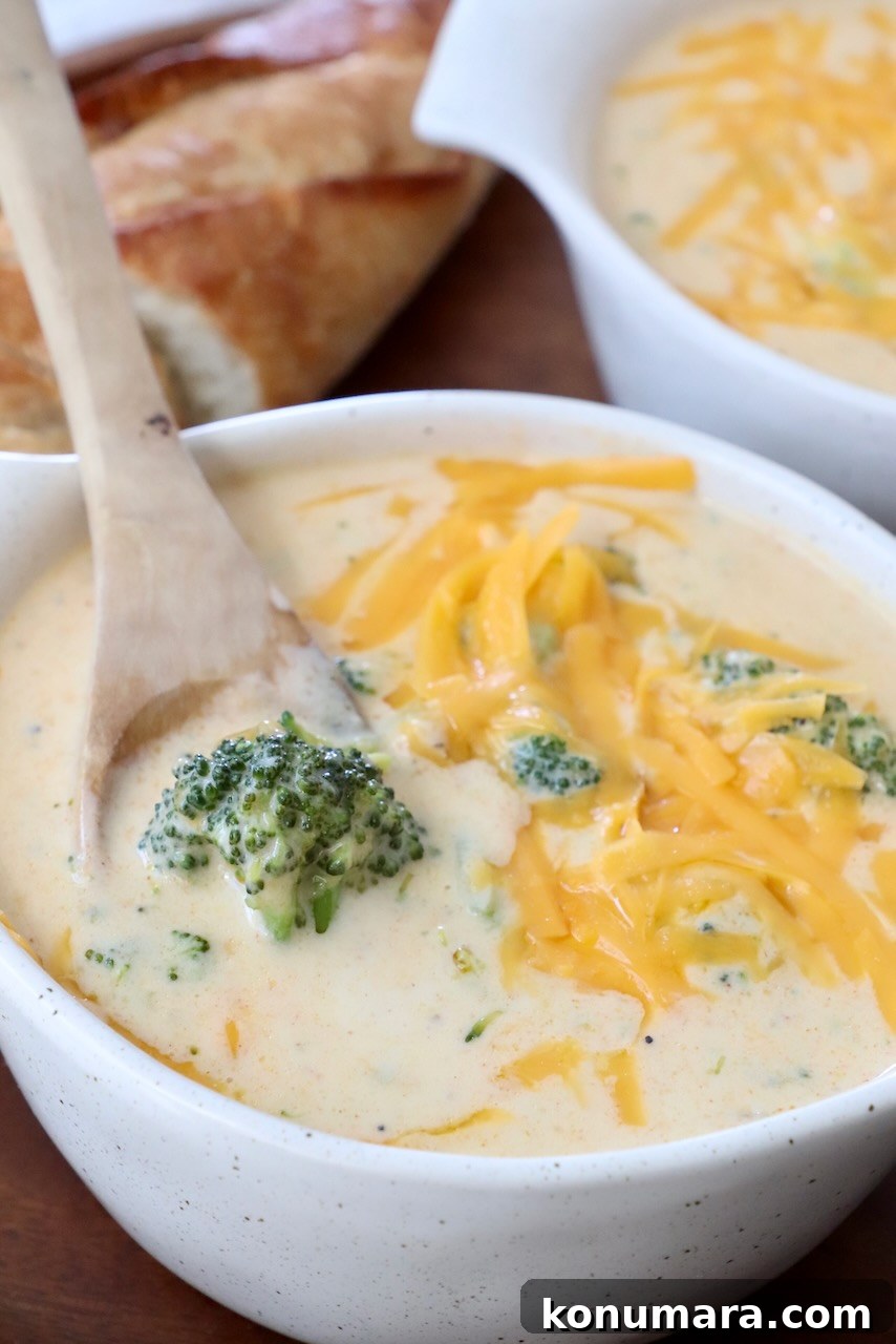 broccoli cheddar soup in bowl with wooden spoon