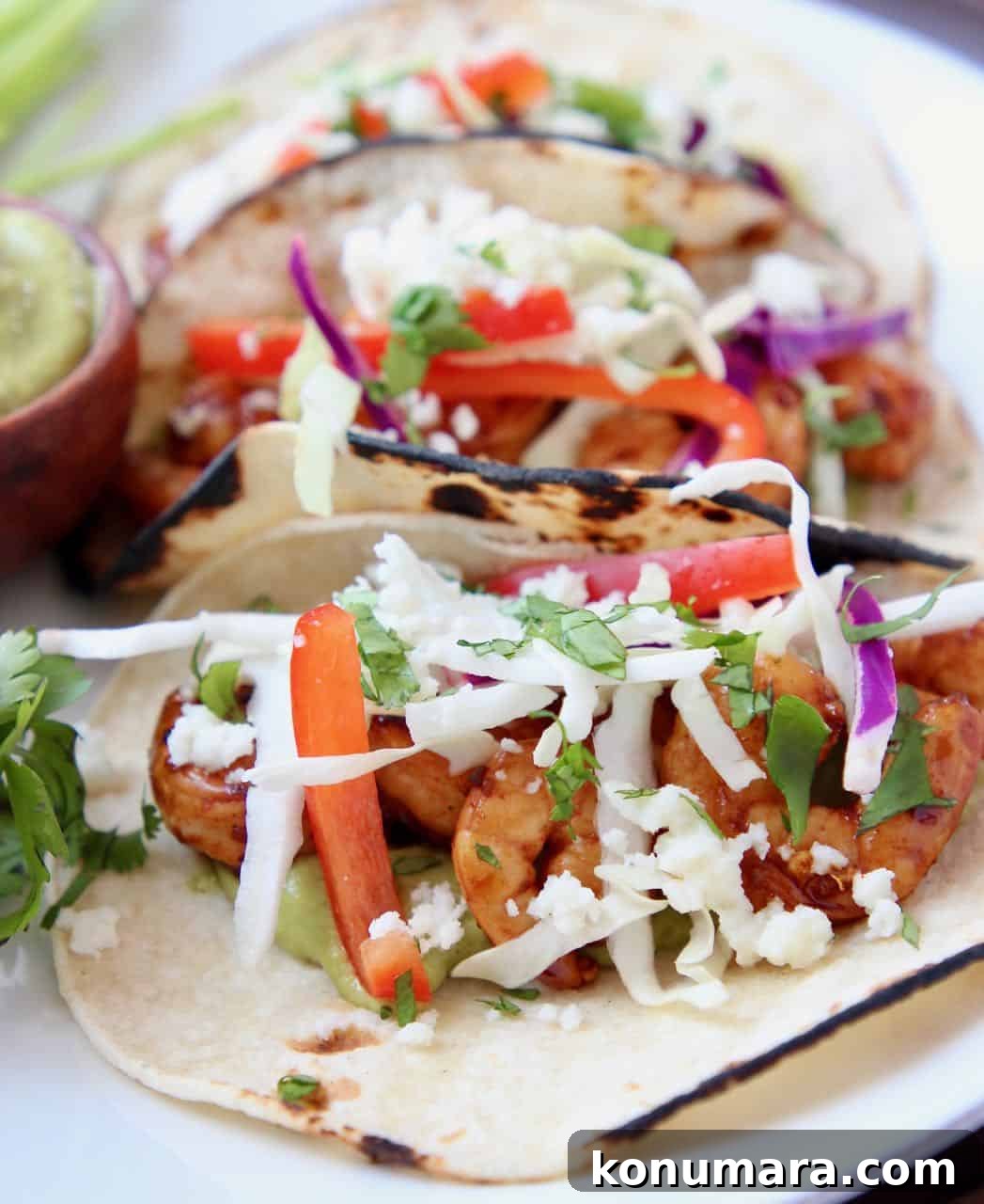 Grilled shrimp tacos, topped with slaw on white plate