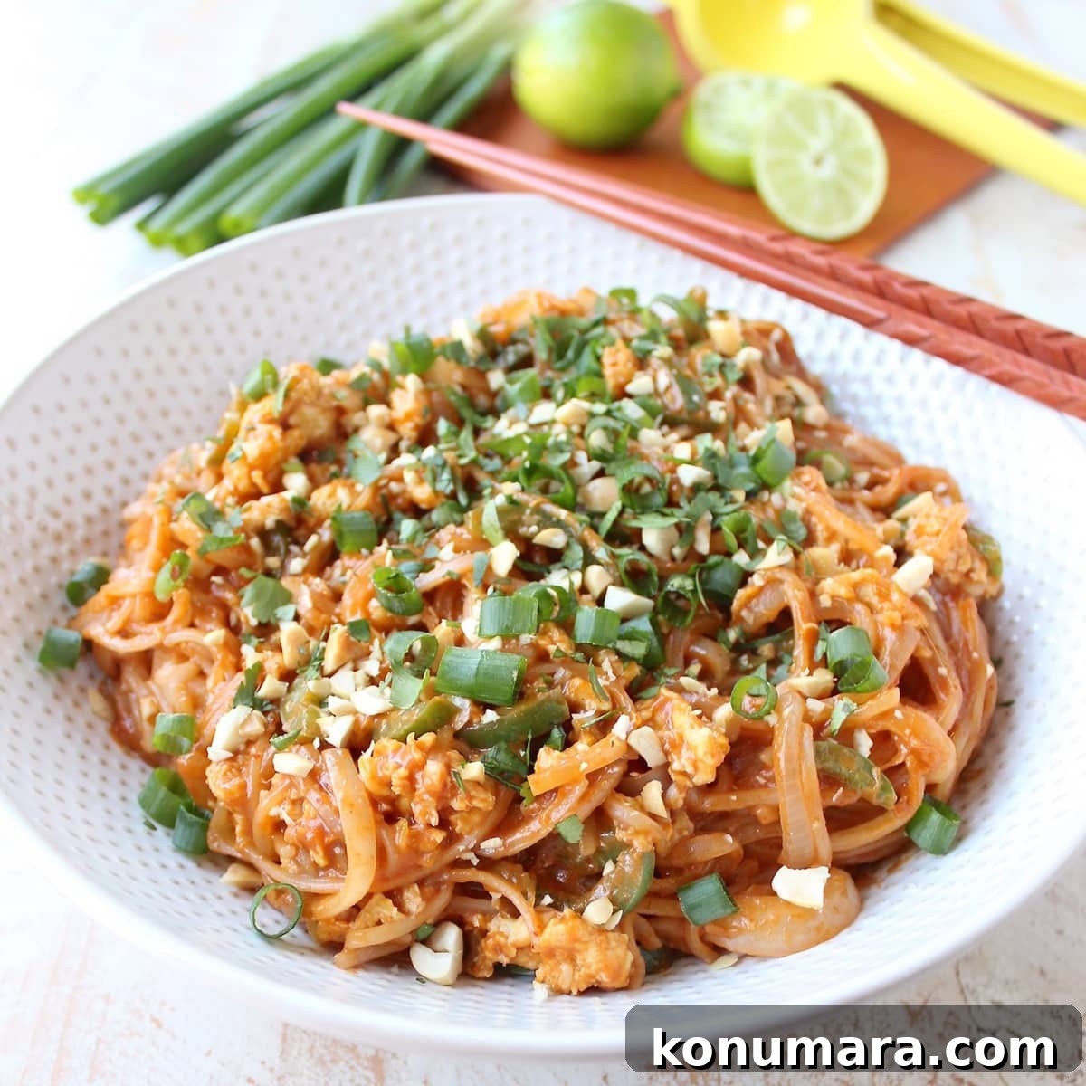 cooked pad thai in bowl topped with diced green onions, crushed peanuts and chopped cilantro