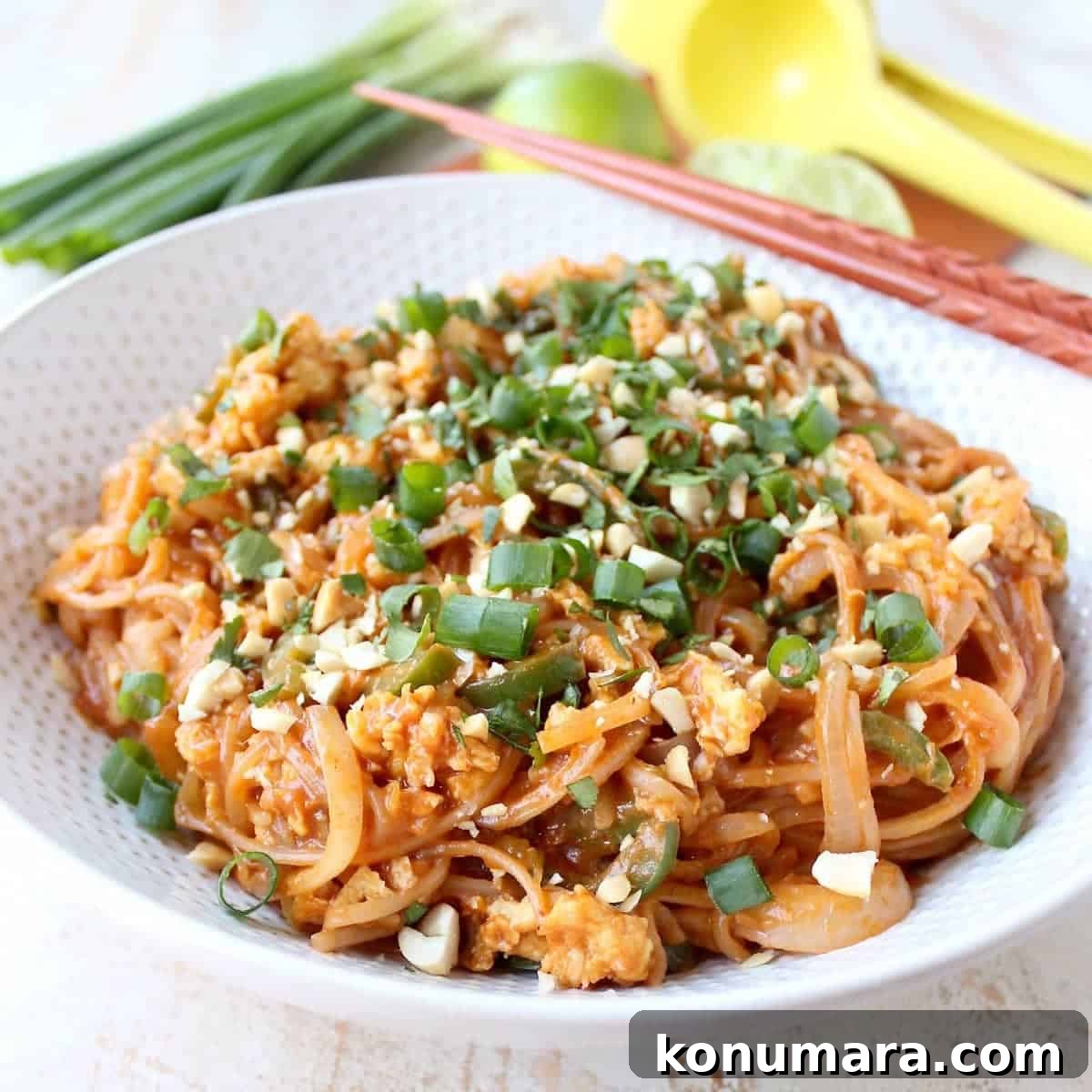 prepared pad thai in bowl with chopsticks on the side
