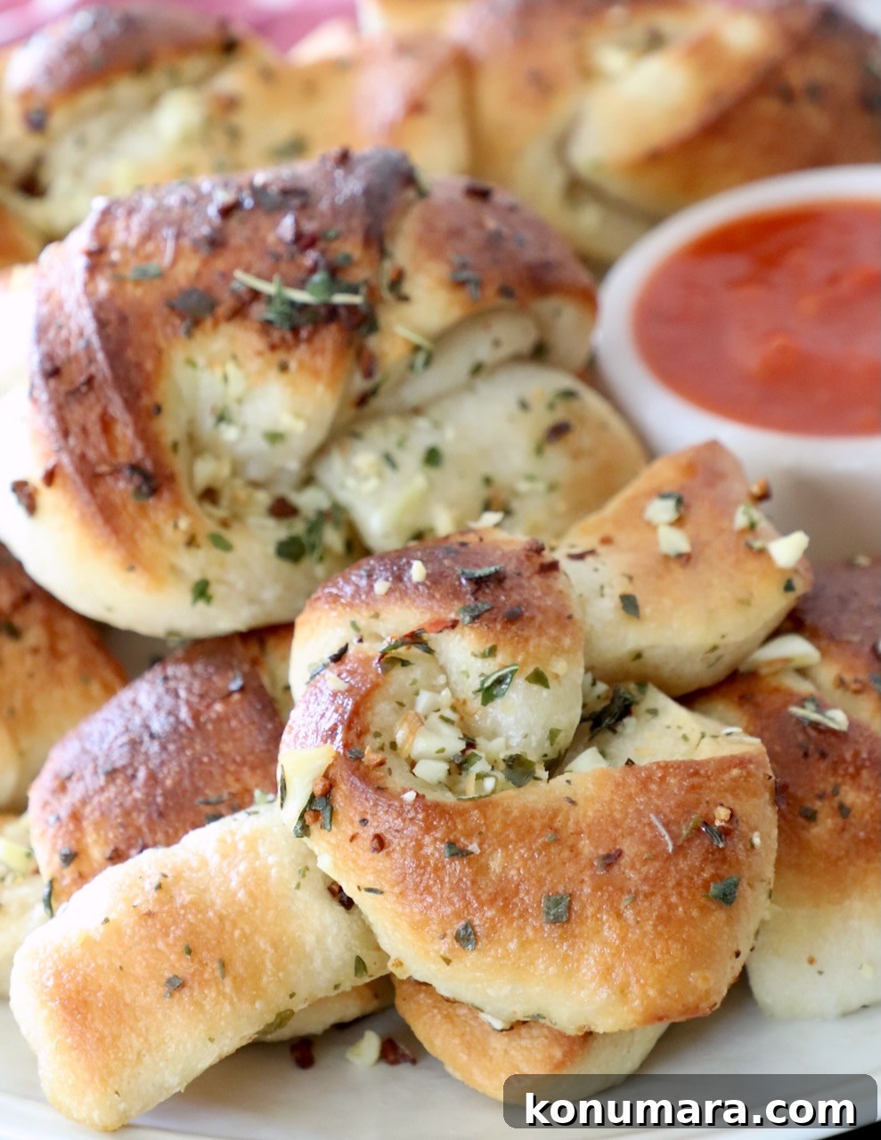 garlic knots on plate with small bowl of marinara sauce