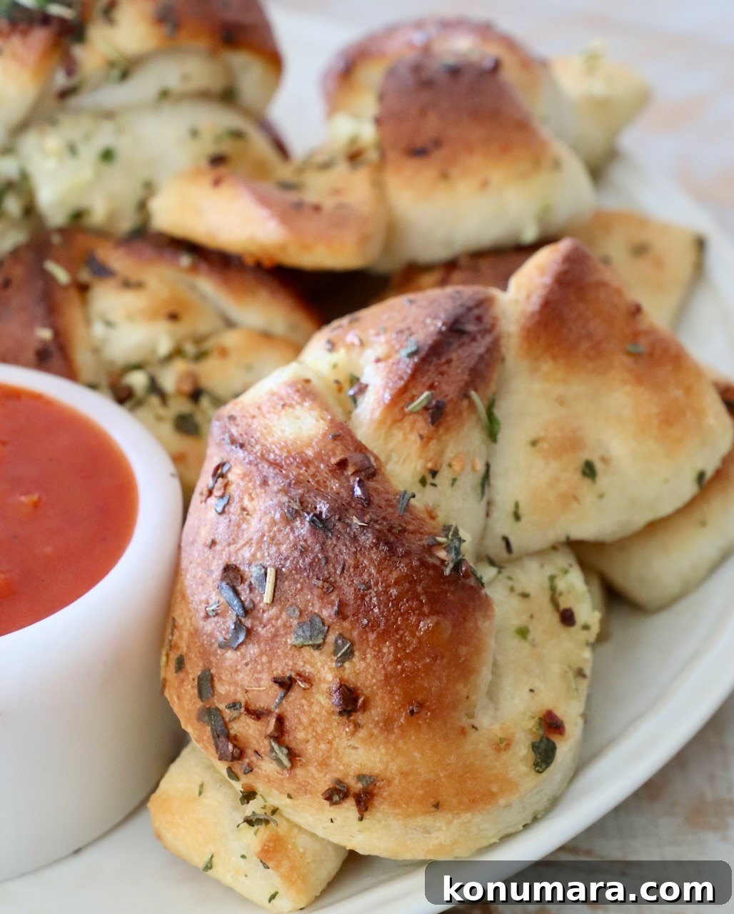 garlic knots on plate with small bowl of marinara sauce