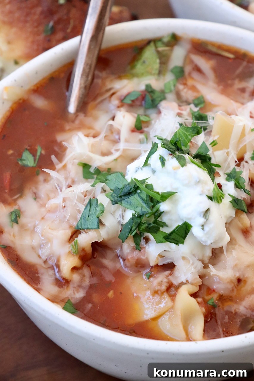 One-Pot Cheesy Lasagna Soup with Italian Sausage 5 lasagna soup topped with ricotta cheese in bowl with spoon