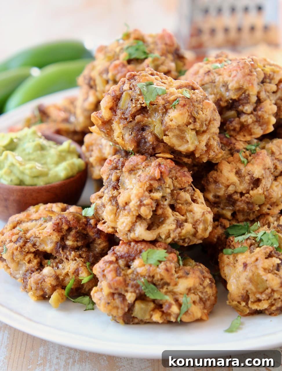 Cheesy Mexican Sausage Balls Recipe with Jalapeno 3 chorizo sausage balls piled on plate with avocado sauce in small wooden bowl