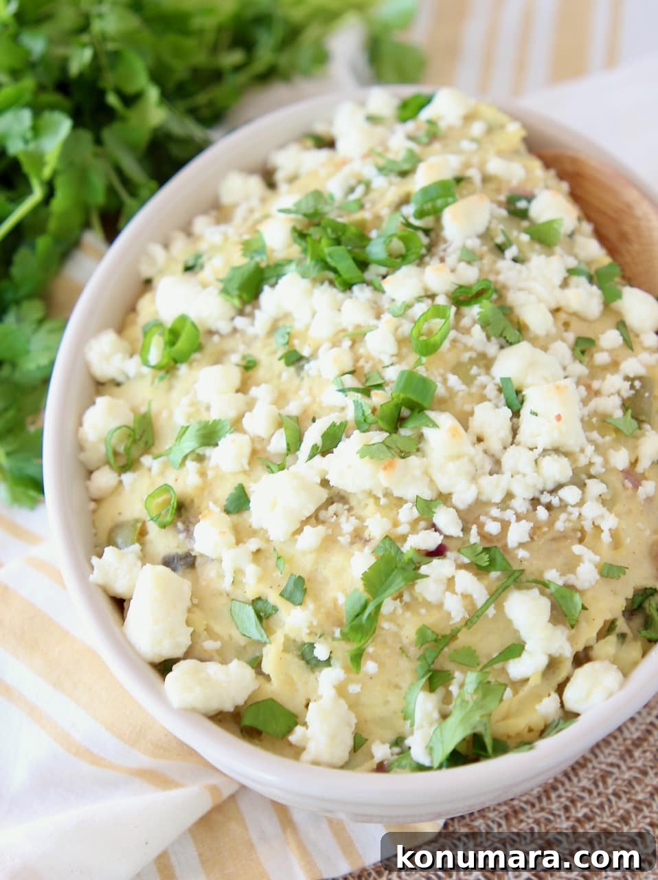 Mexican potatoes mashed in a bowl with queso fresco, diced green onions and fresh cilantro