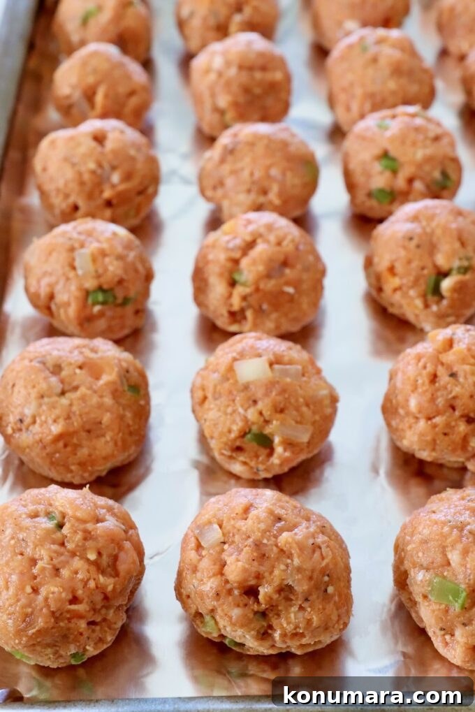 uncooked buffalo chicken meatballs on foil-lined baking sheet