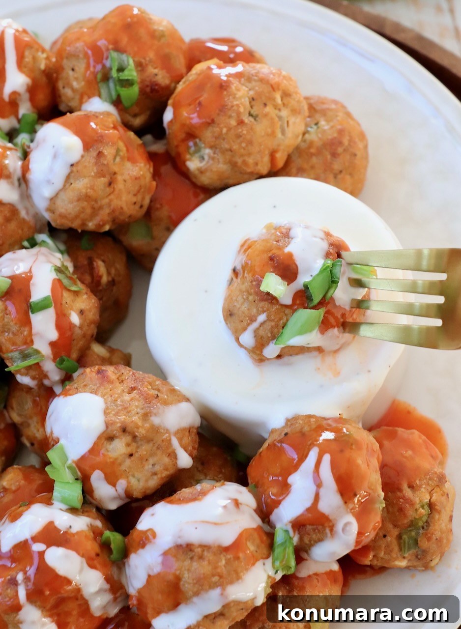 buffalo chicken meatball on fork, dipped into blue cheese dressing in a bowl