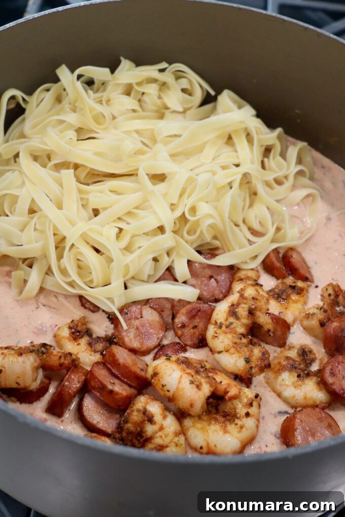 Creamy Cajun Shrimp Pasta with Andouille Sausage 8 cooked pasta, shrimp and sausage added to cajun alfredo sauce in pan