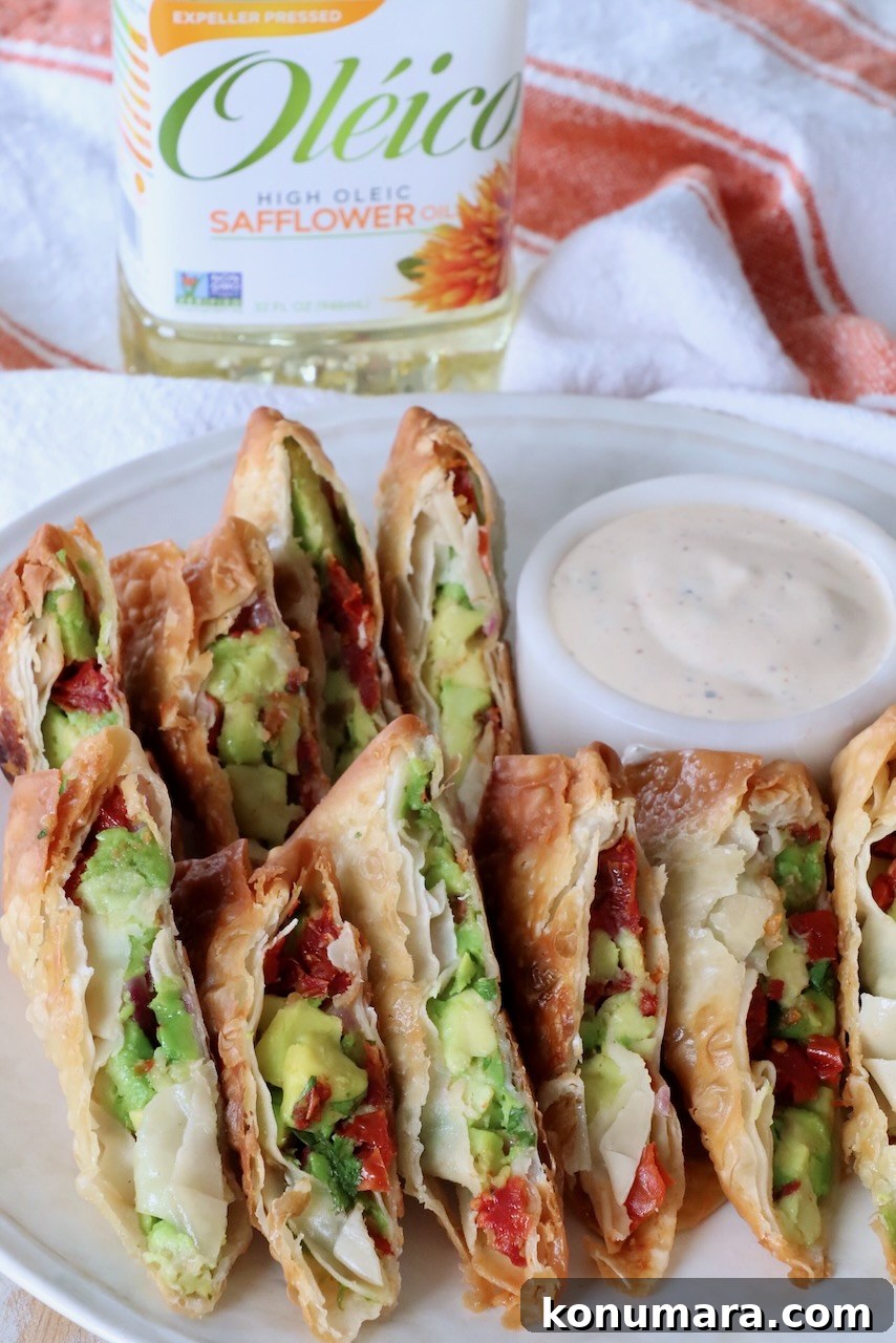 avocado egg rolls sliced in half on a plate with a small bowl of ranch dressing