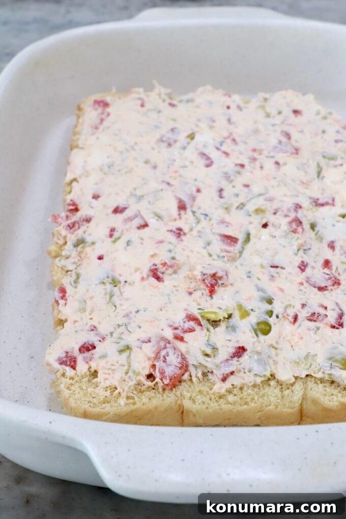 bottom half of rolls, topped with seasoned cream cheese, in casserole dish