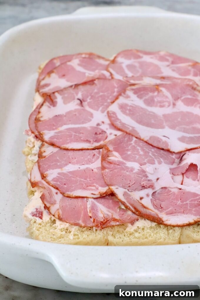 rolls topped with cream cheese and capocollo in casserole dish