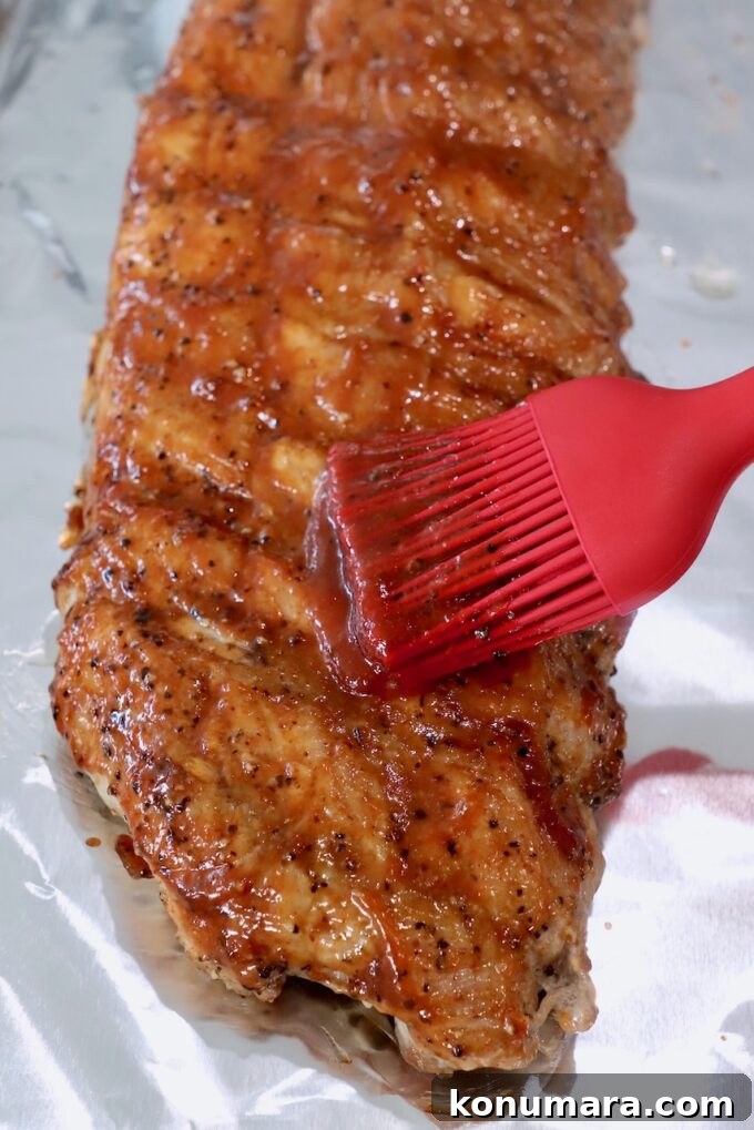 Tender Instant Pot Ribs in 45 Minutes 7 cooked rack of ribs on foil-lined baking sheet, brushed with bbq sauce