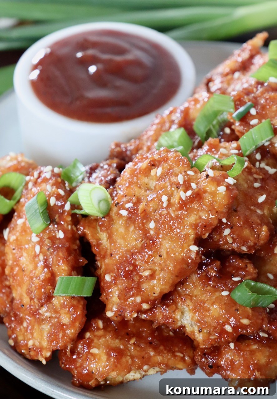 Jack Daniel's BBQ Chicken Strips Recipe 2 cooked chicken strips tossed in bbq sauce on plate topped with diced green onions and sesame seeds