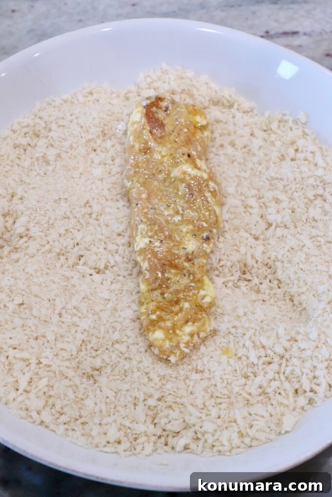 Crispy Air Fryer Chicken Tenders Recipe 8 strip of battered chicken in bowl of breadcrumbs