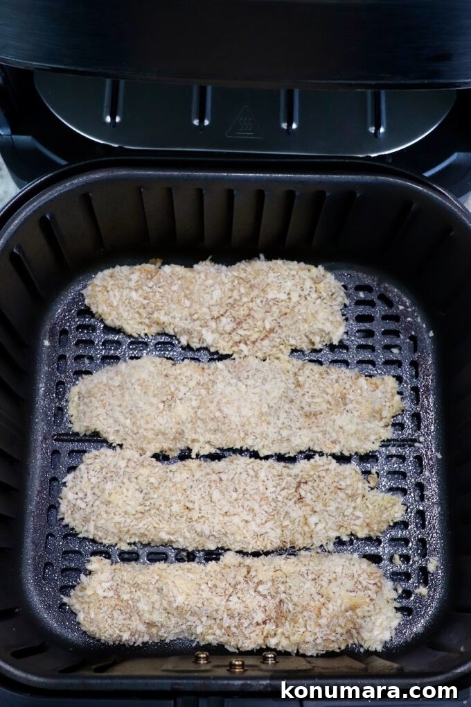 Crispy Air Fryer Chicken Tenders Recipe 10 uncooked breaded chicken tenders in an air fryer basket