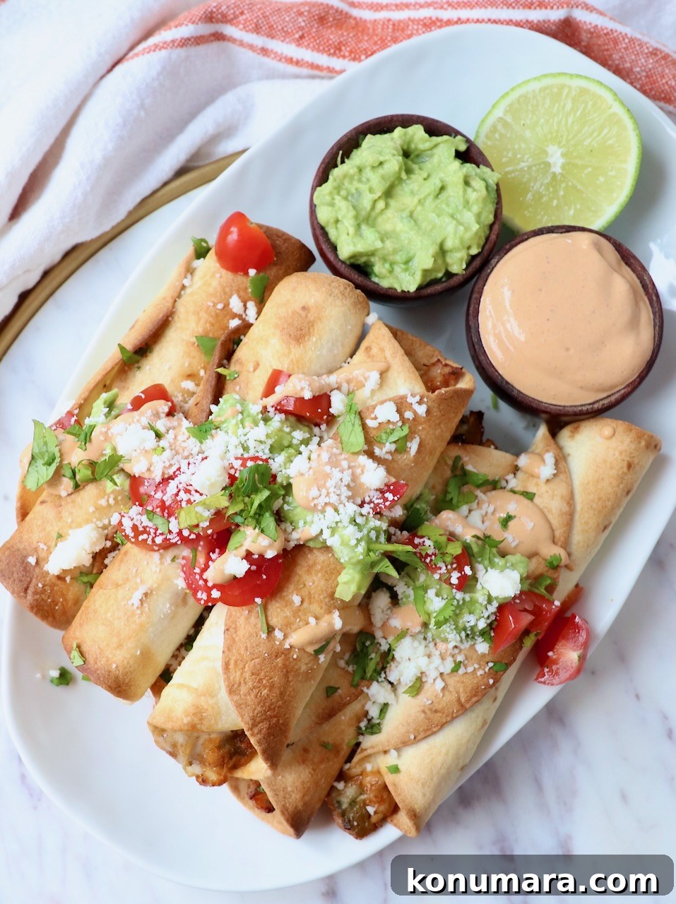 Crispy Air Fryer Taquitos Recipe 2 taquitos stacked up on plate with diced tomatoes and cotija cheese on top