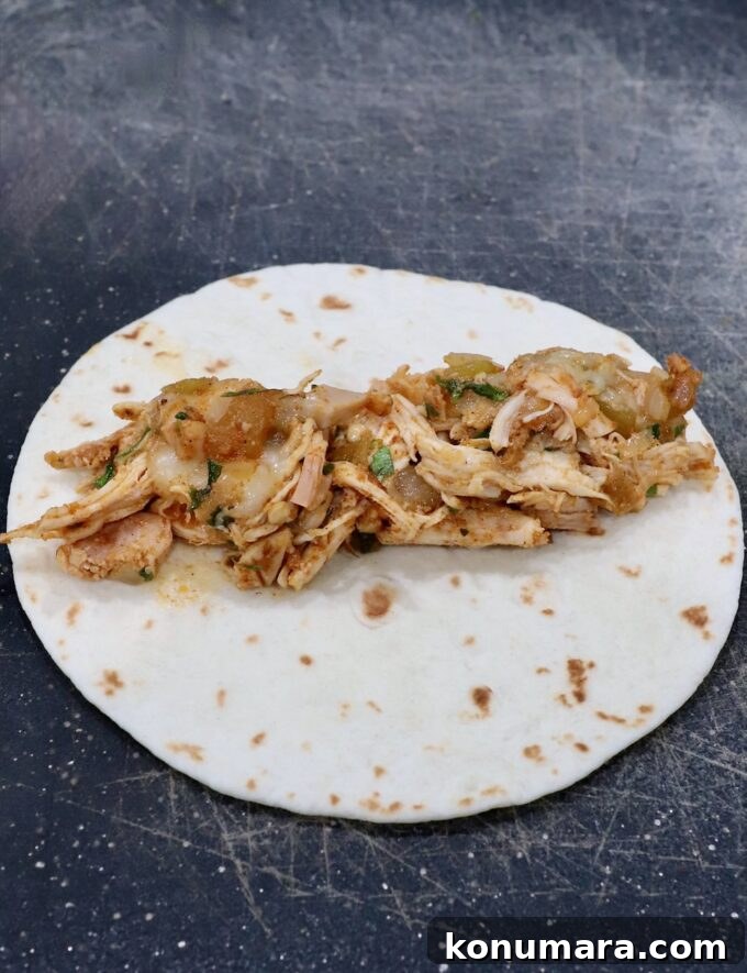 Crispy Air Fryer Taquitos Recipe 8 seasoned shredded chicken and cheese in the middle of a tortilla on a cutting board
