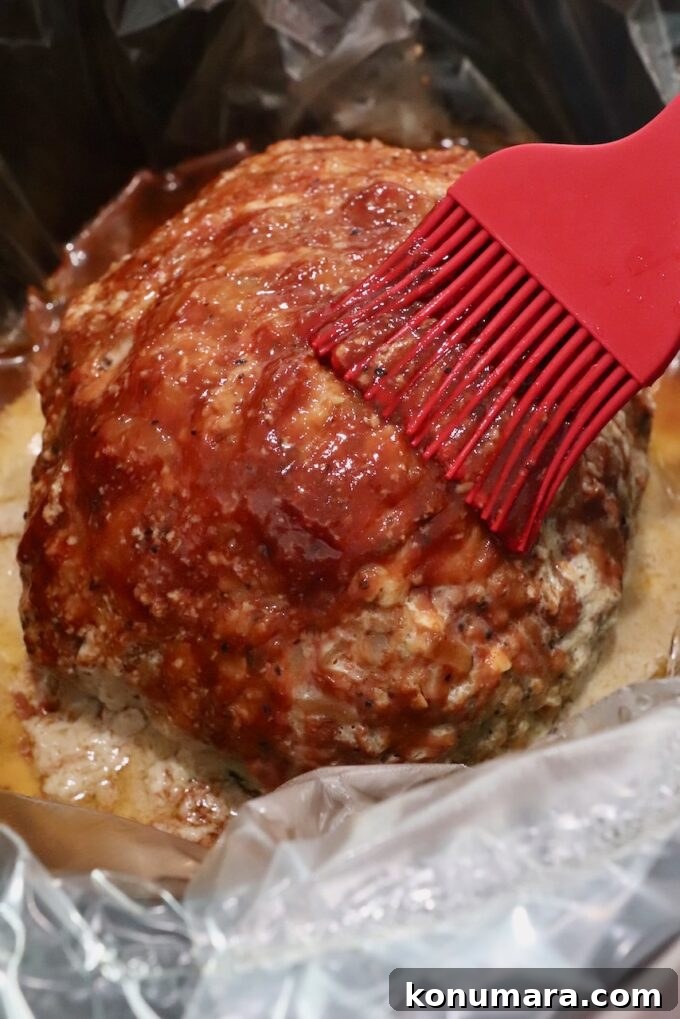 cooked meatloaf in slow cooker brushed with bbq sauce