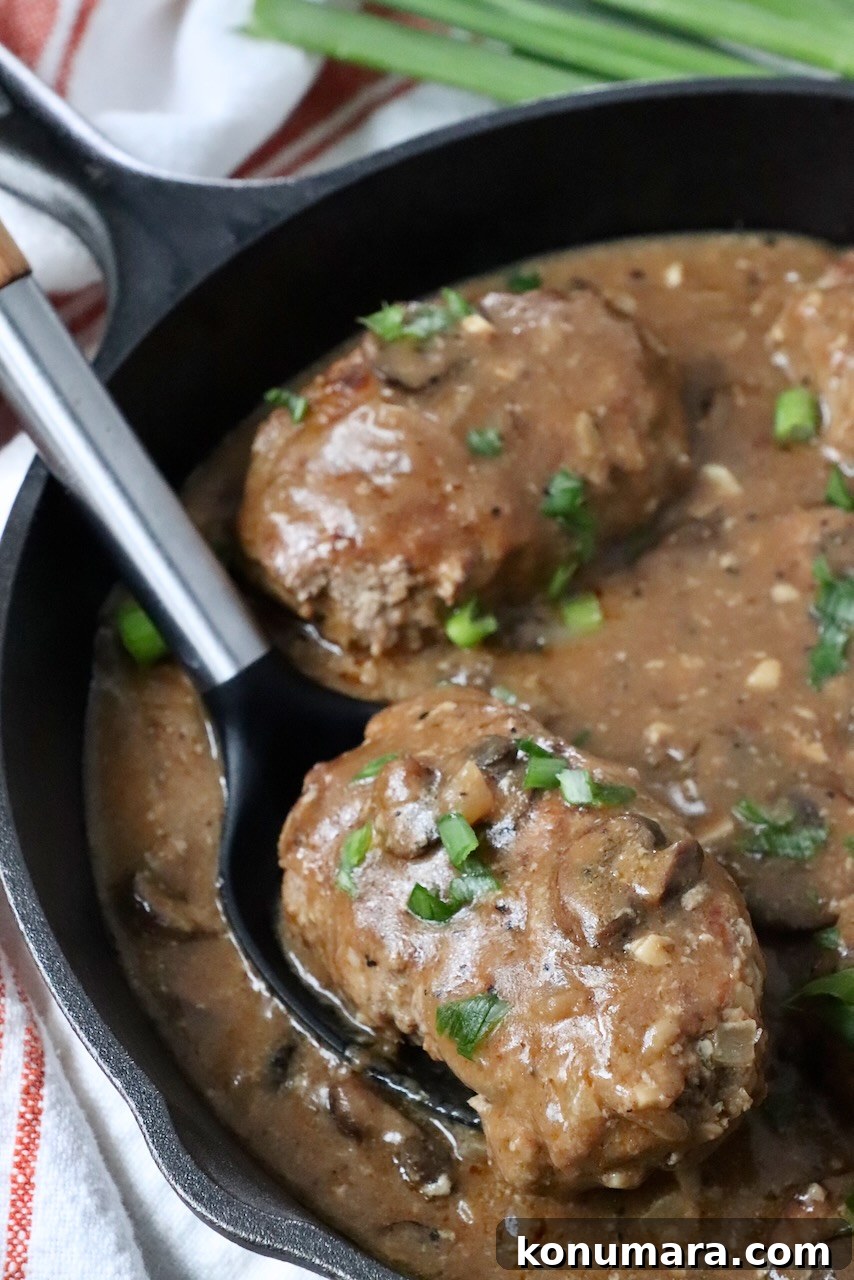salisbury steak lifted up out of skillet with serving spoon