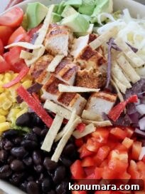 salad in bowl topped with black beans, corn and diced grilled chicken