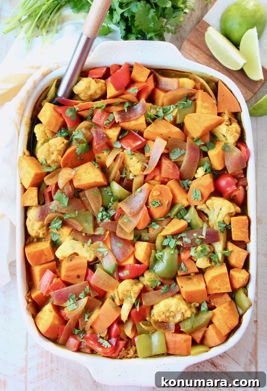 Overhead image of vegetable curry casserole in dish with serving spoon