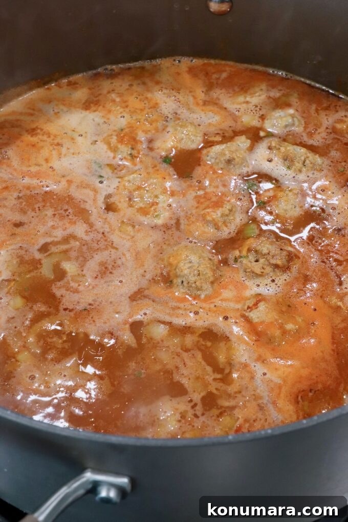 Creamy Buffalo Chicken Soup Recipe 6 meatballs simmering in chicken broth seasoned with buffalo sauce in a large pot