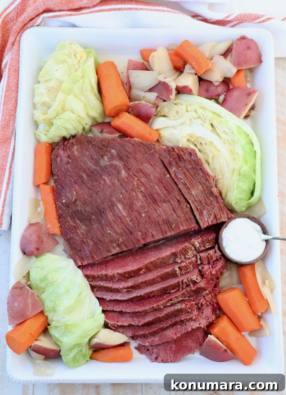 sliced corned beef on serving platter with cabbage, carrots, potatoes and onions
