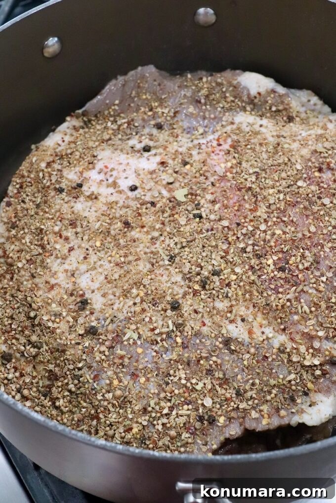 brined beef brisket covered in seasoning in dutch oven