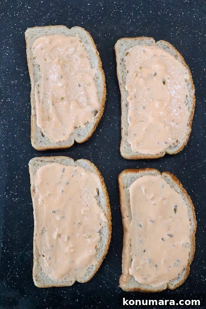 pieces of bread with Thousand Island dressing spread on the bread, on a cutting board