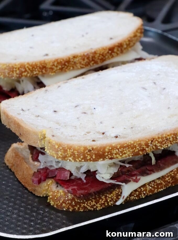 uncooked reuben sandwiches on griddle pan on stove