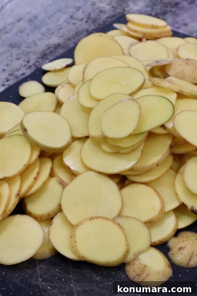 Creamy Garlic and Cheese Scalloped Potatoes Recipe 7 thinly sliced gold potatoes on cutting board
