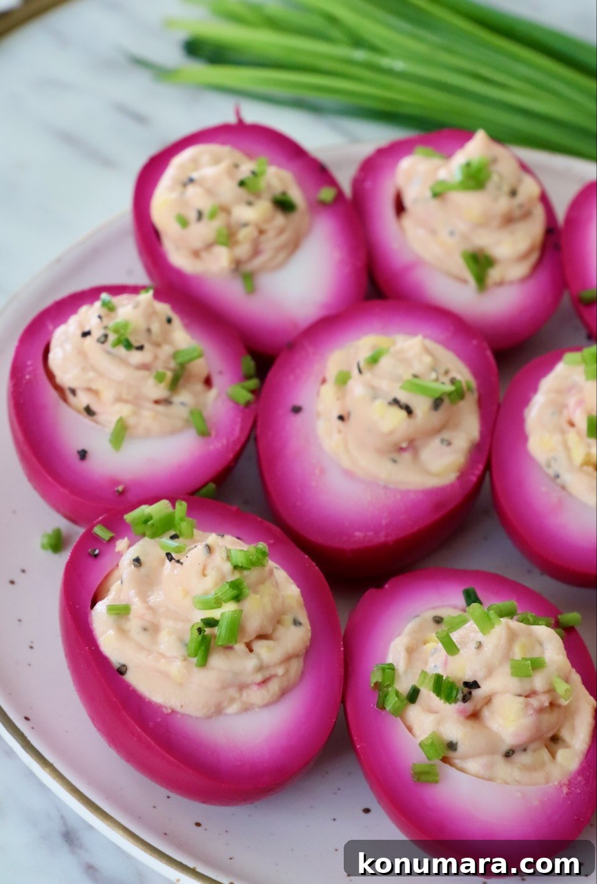 Vibrant Beet Deviled Eggs Recipe with Herbed Filling 2 beet pickled deviled eggs on plate topped with fresh chives