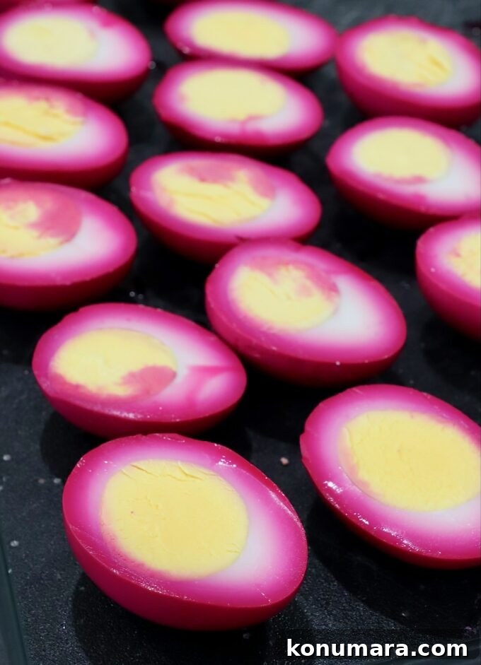 Vibrant Beet Deviled Eggs Recipe with Herbed Filling 5 beet-pickled hard boiled eggs sliced in half on cutting board